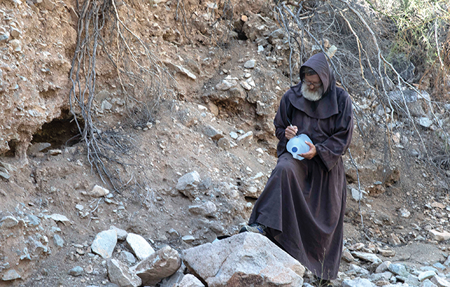 Franciscan Brother David Buer, O.F.M., writes a hopeful message on a water jug. He travels into the desert from his community in Elfrida, Arizona to leave life-saving jugs of water along migrant pathways.